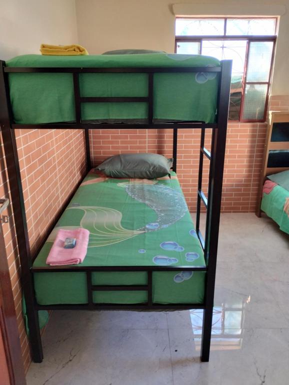 a green bunk bed in a room with a brick wall at Hostel da Ladeira in Ouro Preto