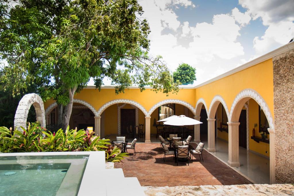 un edificio amarillo con piscina, mesas y sillas en Villa San Antonio de Padua, en Izamal