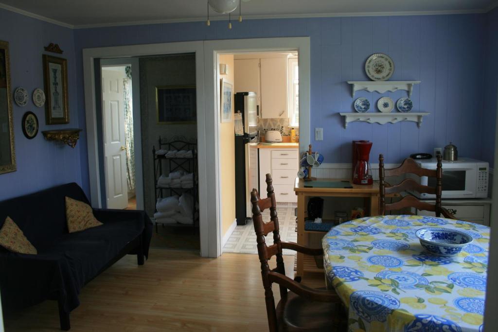 a dining room with a table and a kitchen at Simply Charming Cottages in Cavendish