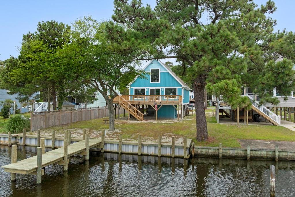 a blue house on the water with a dock at Sunbeam Sands in Kill Devil Hills