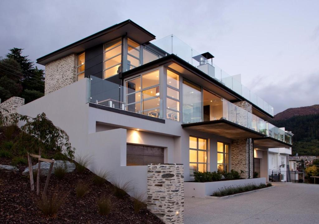 a house with large glass windows on the side of it at Kakara Moana by MajorDomo - Lake Views & Spa Pool in Queenstown