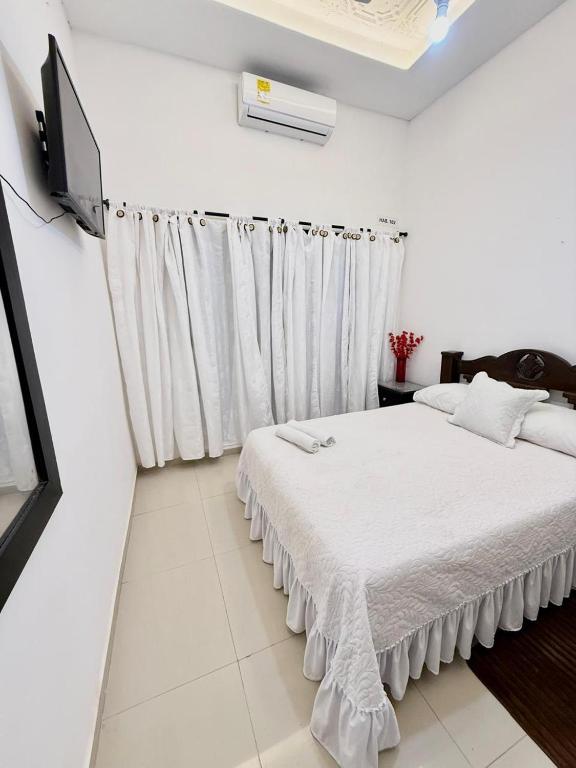 Casa Eme Hostal في كارتاهينا دي اندياس: غرفة نوم بيضاء مع سرير وتلفزيون