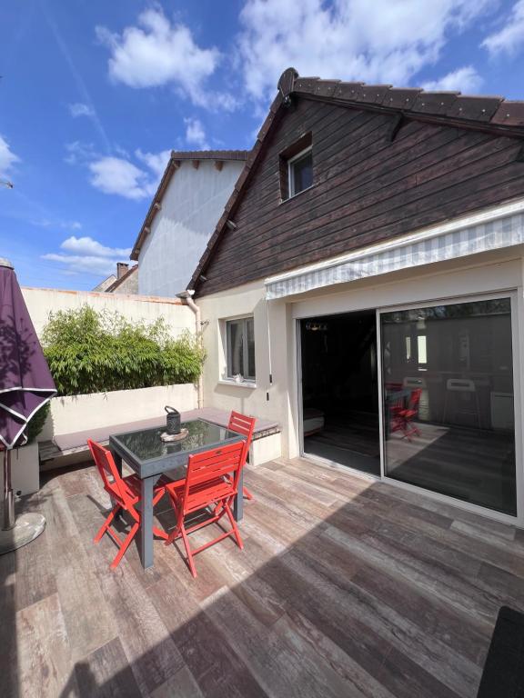 a patio with red chairs and a table on a deck at Le loft in Villeneuve-Saint-Georges