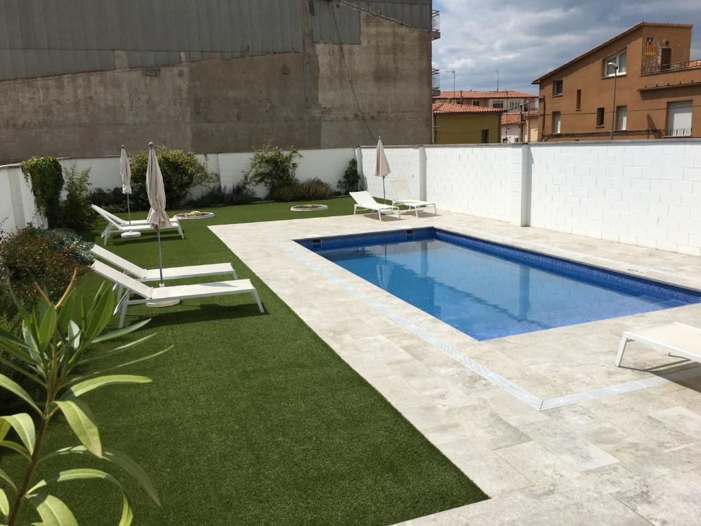 a swimming pool with two lawn chairs and a swimming pool at Can Beliu in Roda del Ter