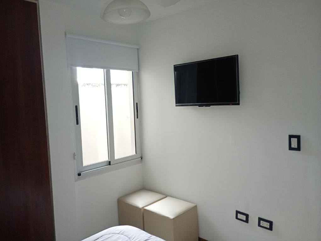 Habitación blanca con TV y ventana en Sueños, en Villa Carlos Paz