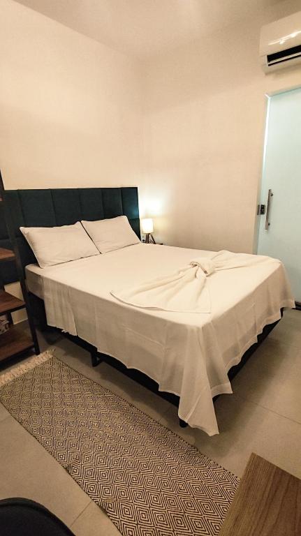 a bedroom with a large bed with white sheets at Studio 61- No Coração de Curvelo in Curvelo