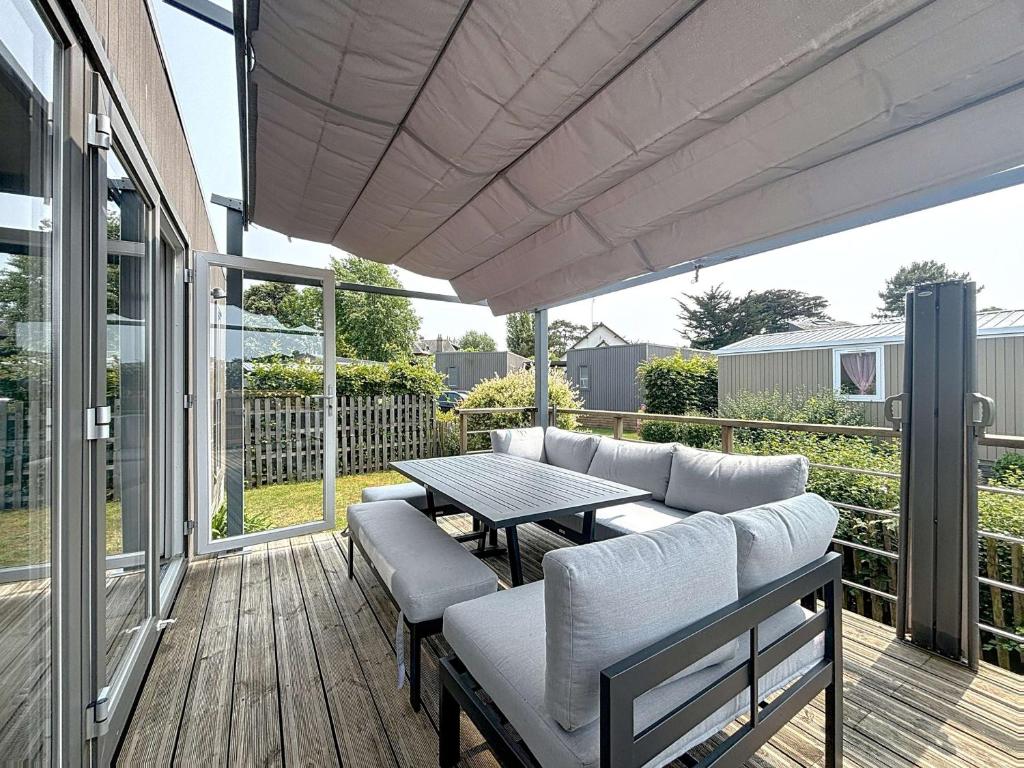 d'une terrasse avec une table et des canapés. dans l'établissement Mobil-home moderne 3 chambres, terrasse, animaux admis - FR-1-361A-97, à Jullouville