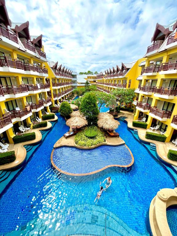 a pool at a resort with people swimming in it at Woraburi Phuket Resort & Spa - SHA Plus in Karon Beach
