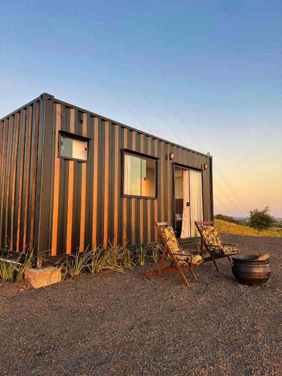 a tiny house with a couple of chairs in front of it at Hospedagem Morro do Buda Container in Planalto