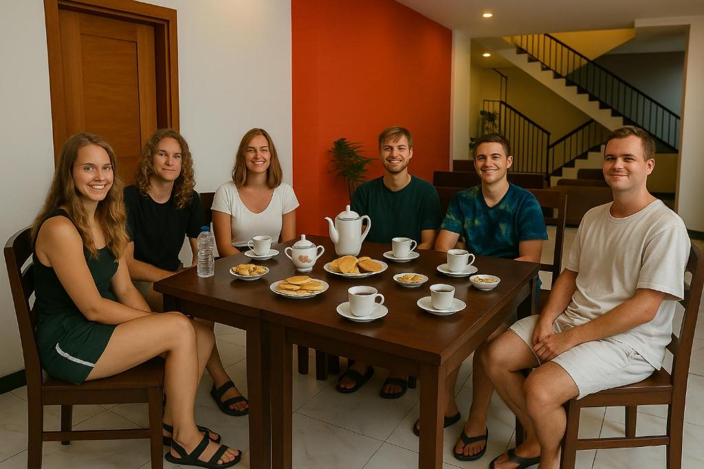 un gruppo di persone seduti intorno a un tavolo di Marine Hostel at Negombo Beach a Negombo