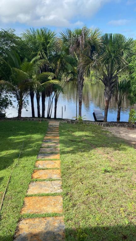 a pathway in a park with palm trees and water at Casa do RIO in Barreirinhas