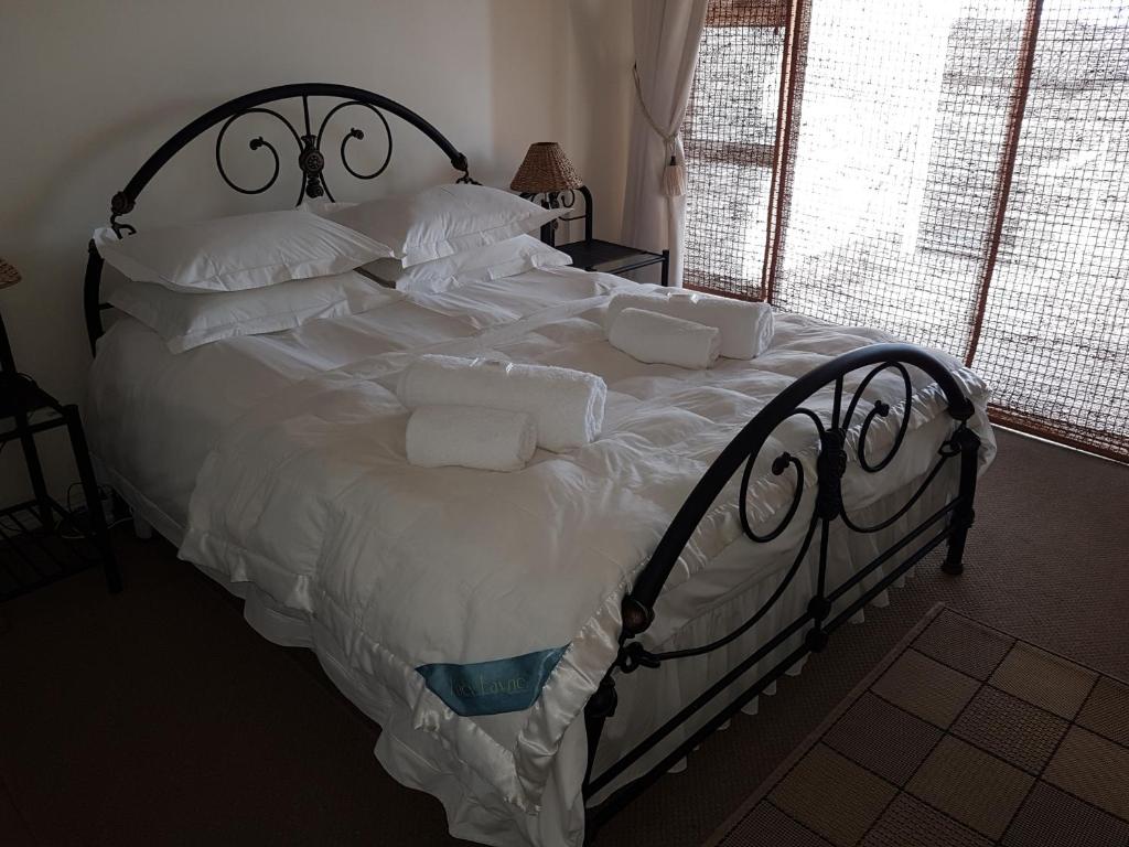 a large bed with white sheets and pillows at Bradclin Beach Blouberg in Big Bay