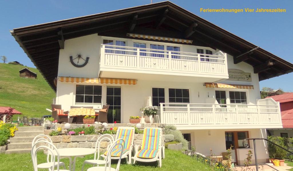 ein weißes Haus mit Stühlen davor in der Unterkunft Ferienwohnung Vier Jahreszeiten in Hirschegg