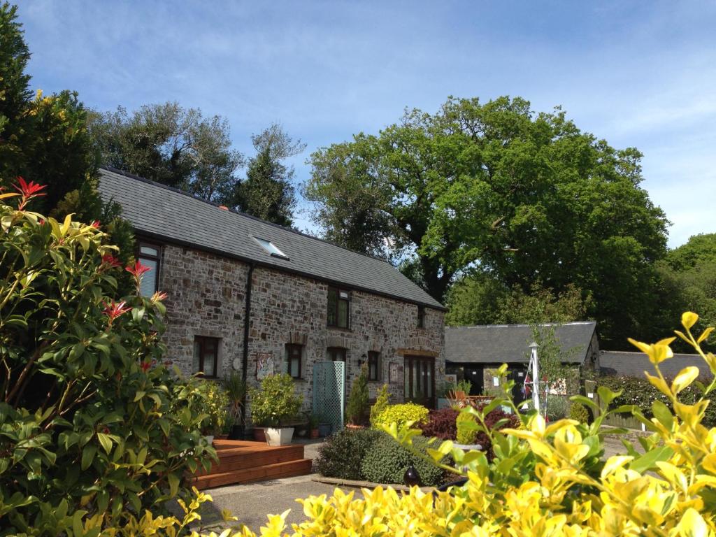 een bakstenen huis met een tuin ervoor bij Petrock Holiday Cottages in Newton Saint Petrock