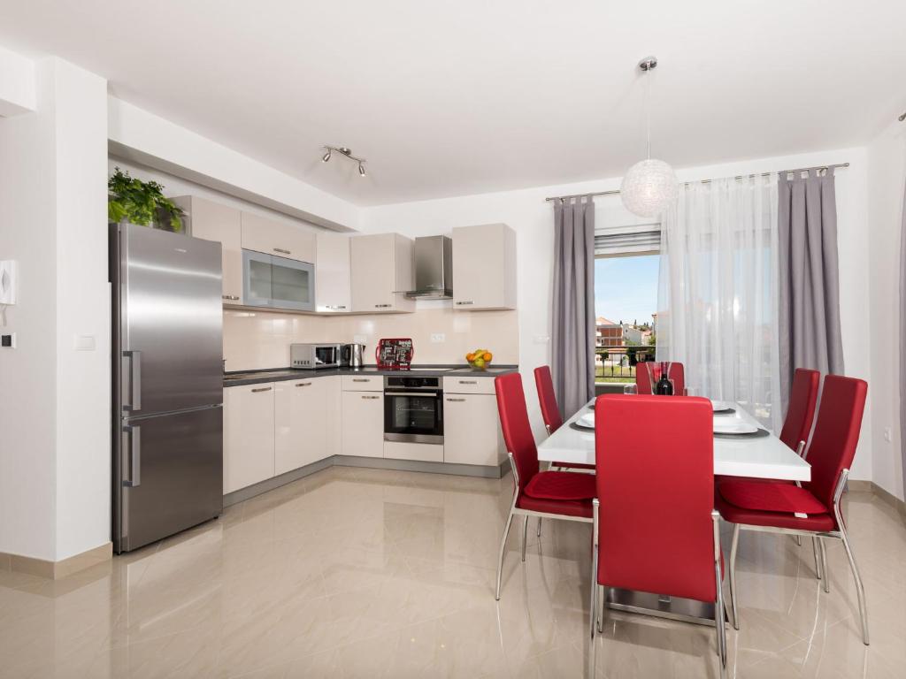 a kitchen with a dining table and red chairs at Apartment Bingo in Trogir