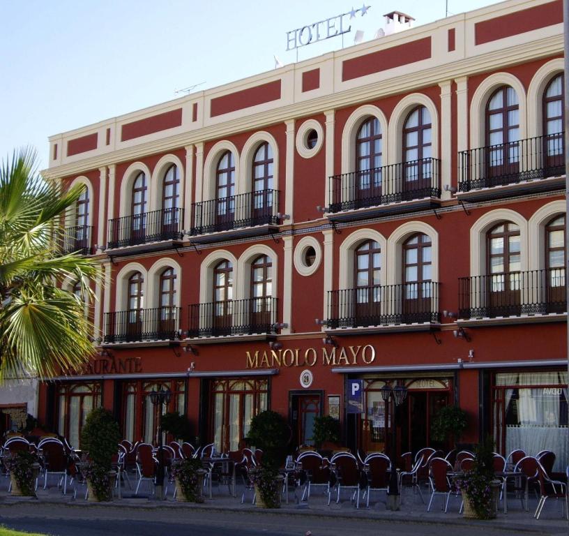 un edificio rosso con sedie di fronte di Hotel Manolo Mayo a Los Palacios y Villafranca