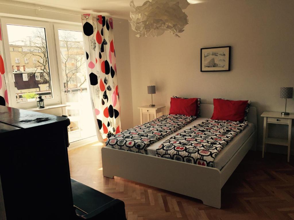 Un dormitorio con una cama con almohadas rojas y una ventana en Apartament KoKi Retro, en Gdynia