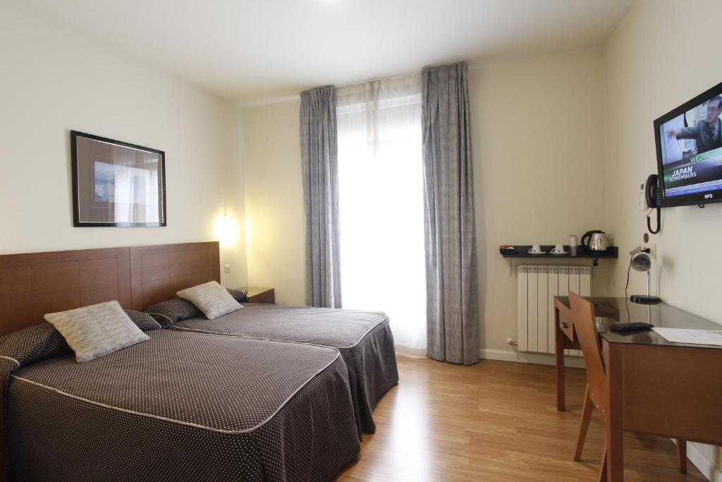 a bedroom with a bed and a table and a desk at Rincón de Gran Vía in Madrid