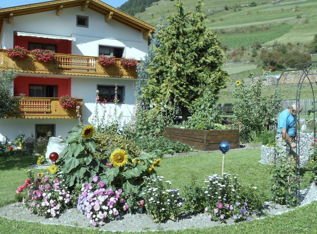 a man standing in front of a house with flowers at Haus Sagl in Nauders
