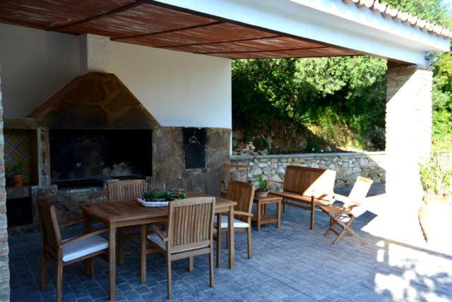 a patio with a table and chairs and a fireplace at Mirador de Mulera in Ubrique