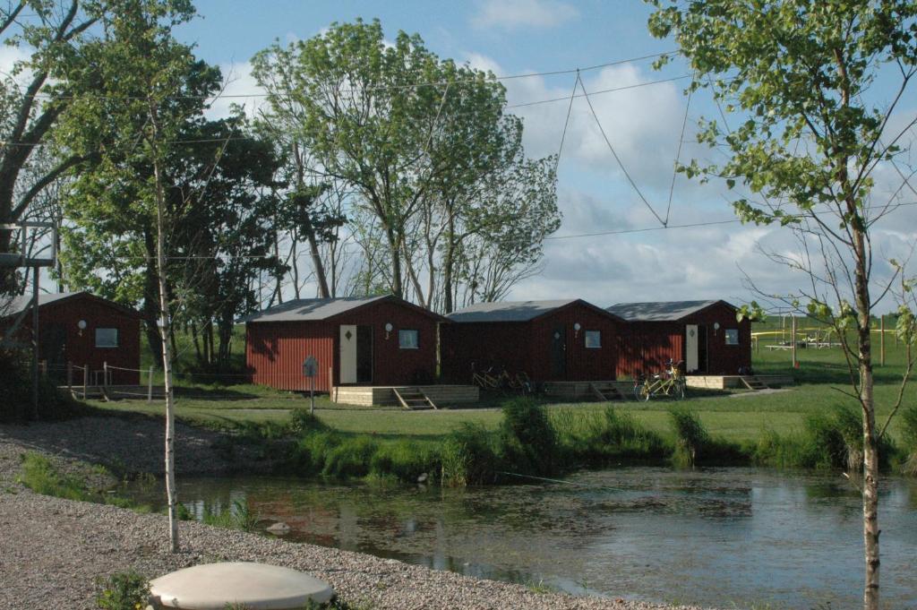 un grupo de edificios con un río y árboles en Natursköna Gamlegård på Ön Ven en Sankt Ibb