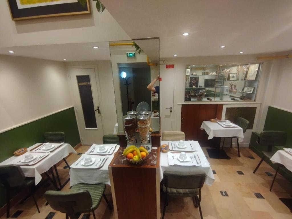 a restaurant with tables and chairs and a person standing in the mirror at Hotel Modern Est in Paris