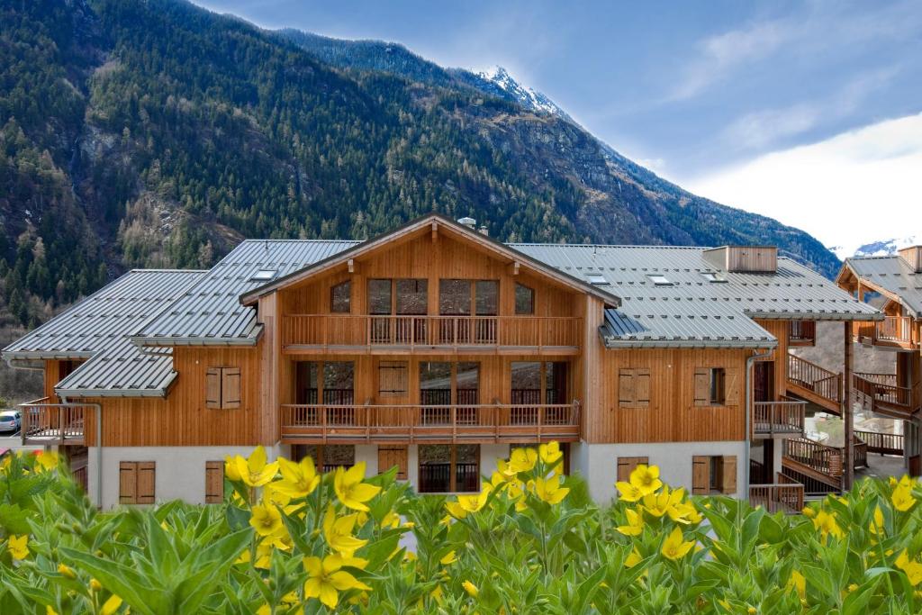 une grande maison en bois avec une montagne en arrière-plan dans l'établissement Résidence Orelle 3 vallées by AltiResid, à Orelle