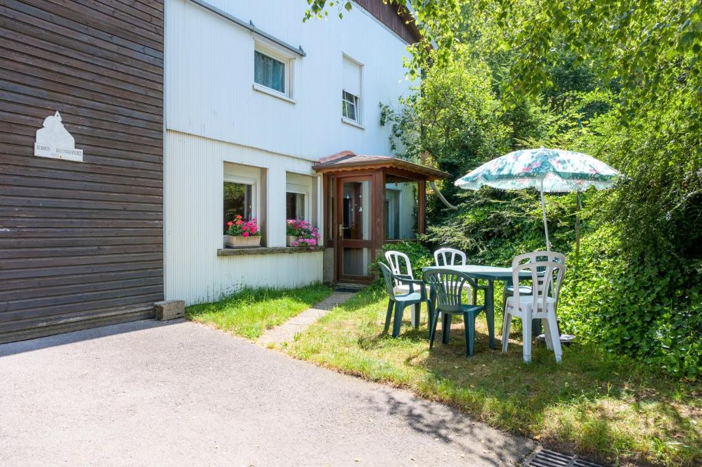- une table et des chaises avec un parasol en face d'une maison dans l'établissement Appartement Atypique, à La Bresse