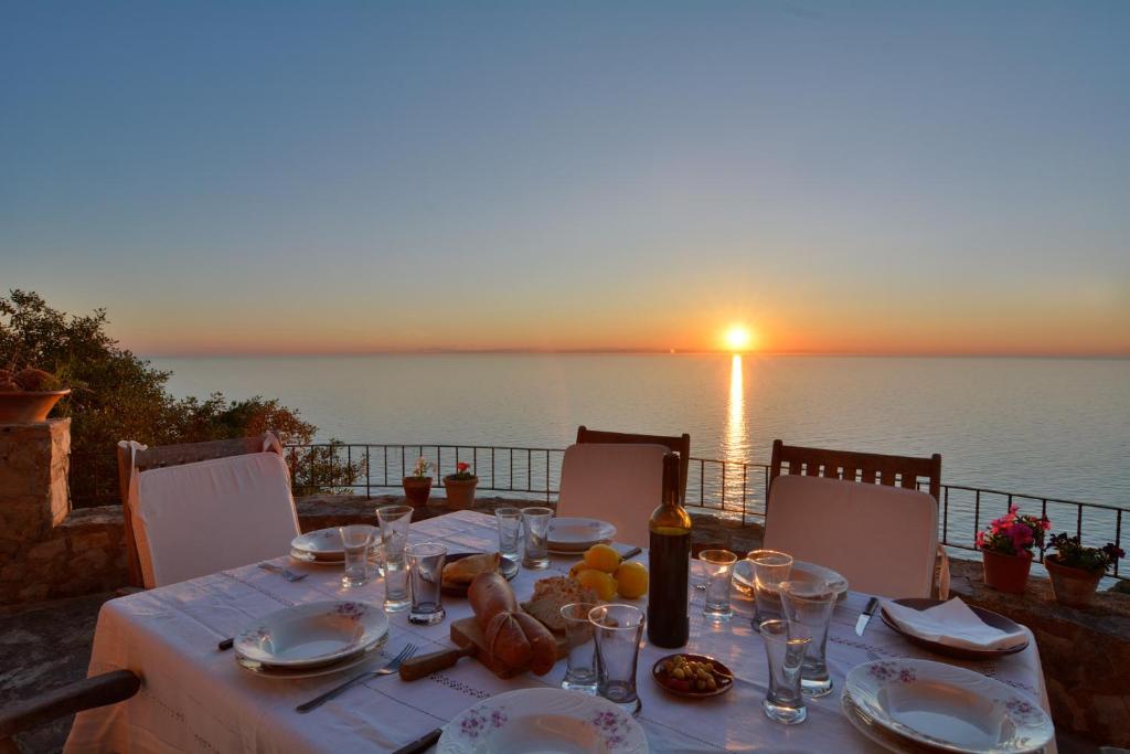 a dinner table with a view of the ocean at sunset at Sa Cova Banyalbufar in Banyalbufar