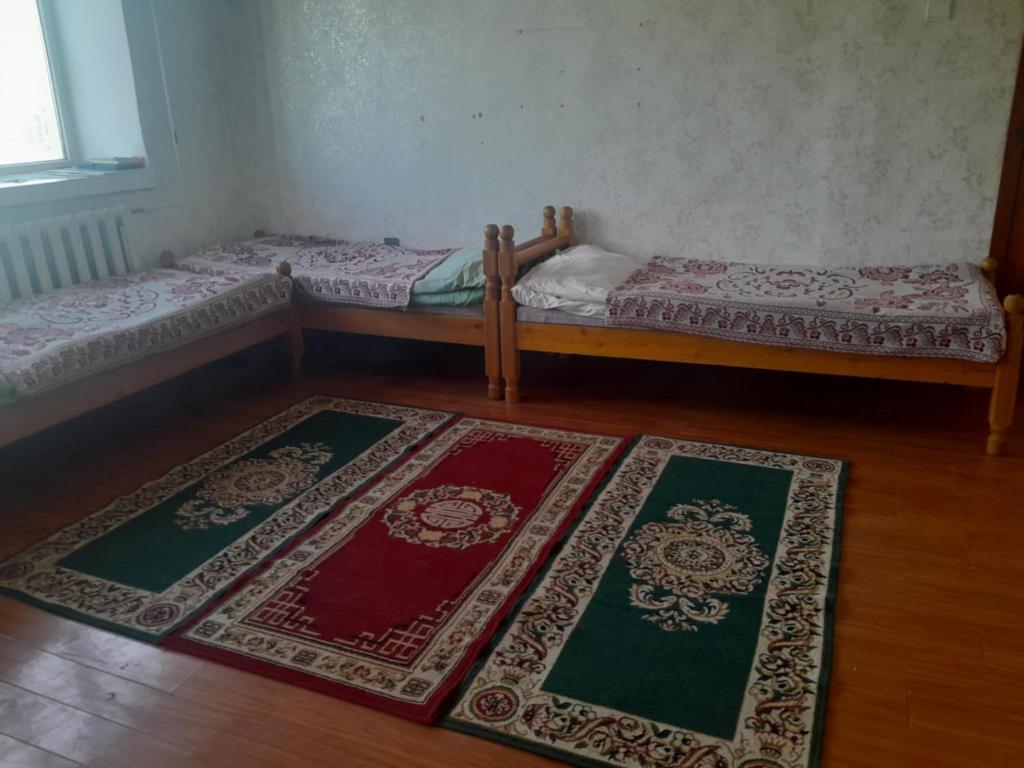 two beds in a room with rugs on the floor at Munkhut guest house in Mörön