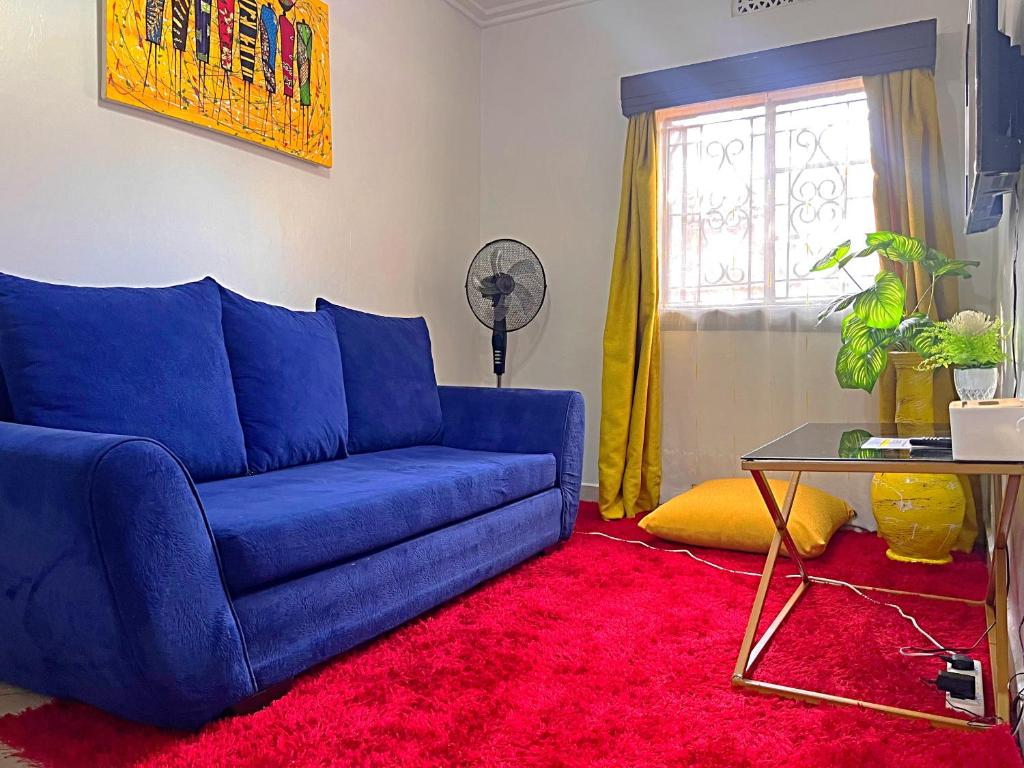 ein blaues Sofa im Wohnzimmer mit einem roten Teppich in der Unterkunft Lovely Homely APT 1BR in Kisumu