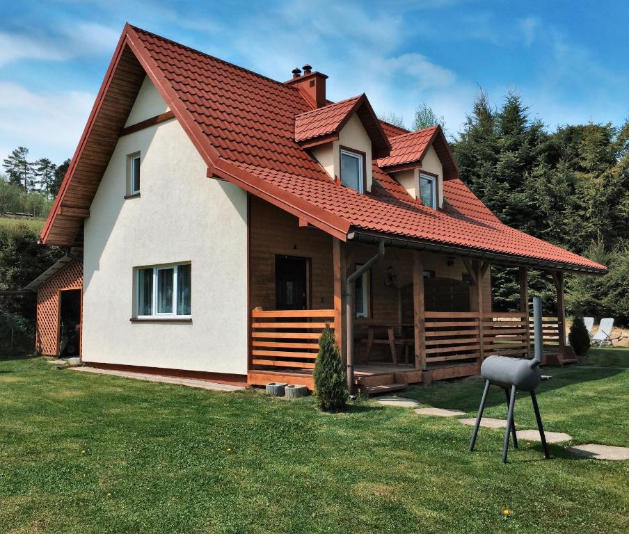 a house with an orange roof on the grass at Bieszczady111 - domki in Polańczyk
