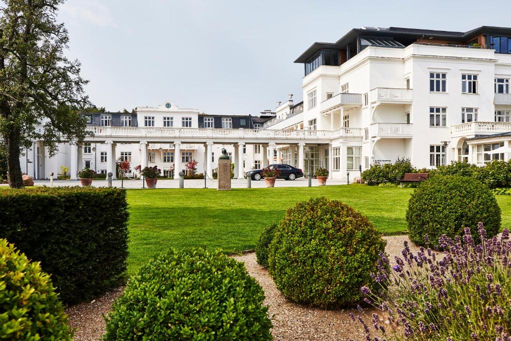 a large white building with bushes in front of it at Kurhotel Skodsborg in Skodsborg