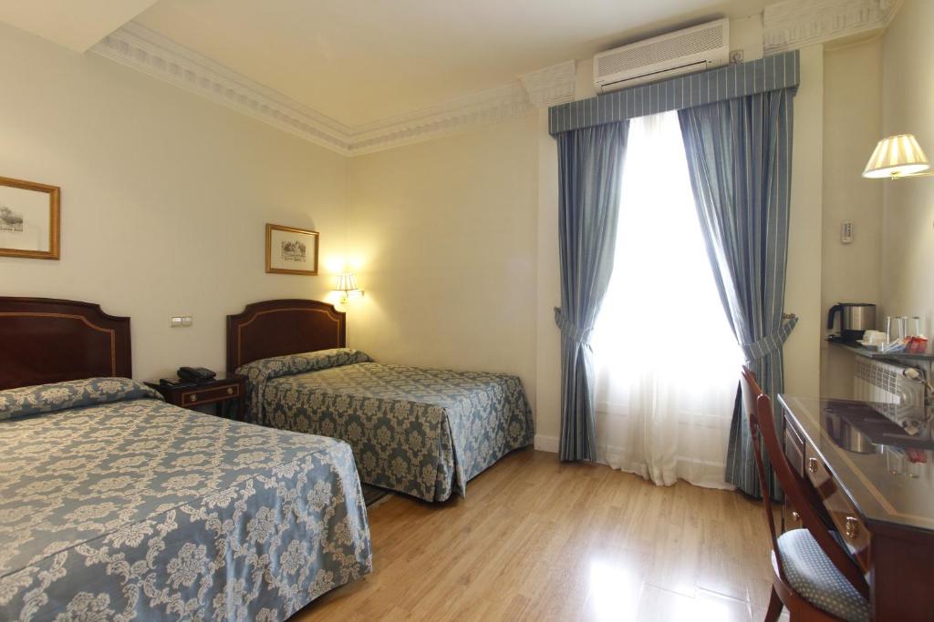 a hotel room with two beds and a window at Rincón de Gran Vía in Madrid