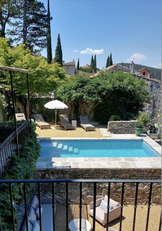 une piscine avec des chaises et un parasol dans l'établissement Le Mûrier, à Vaison-la-Romaine