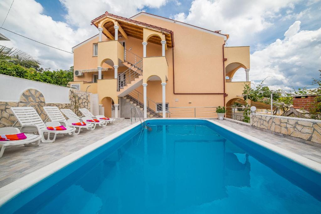 a villa with a swimming pool in front of a house at Apartments Saldun in Trogir