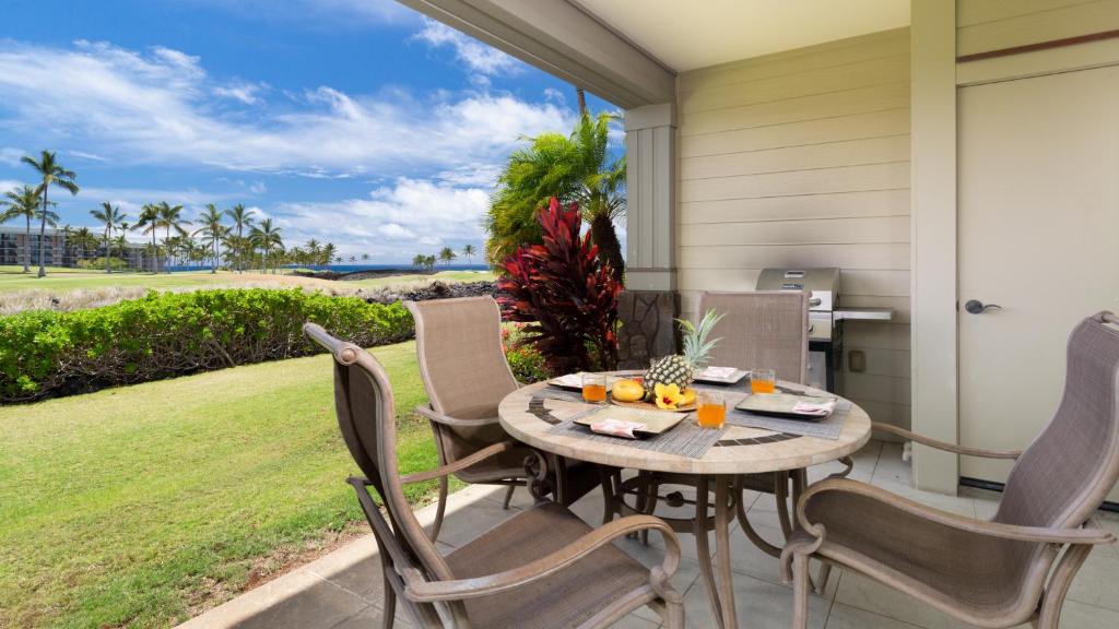 a table and chairs on a patio with a view of the ocean at BY THE SEA VILLA Cheerful 3BR Halii Kai Home with Golf and Ocean Views in Waikoloa