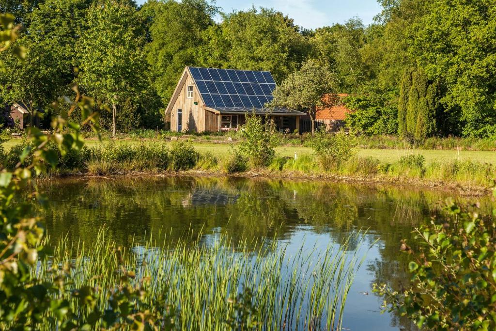 ein Haus mit Sonnenkollektoren auf dem Dach neben einem See in der Unterkunft het Atelier in Eext