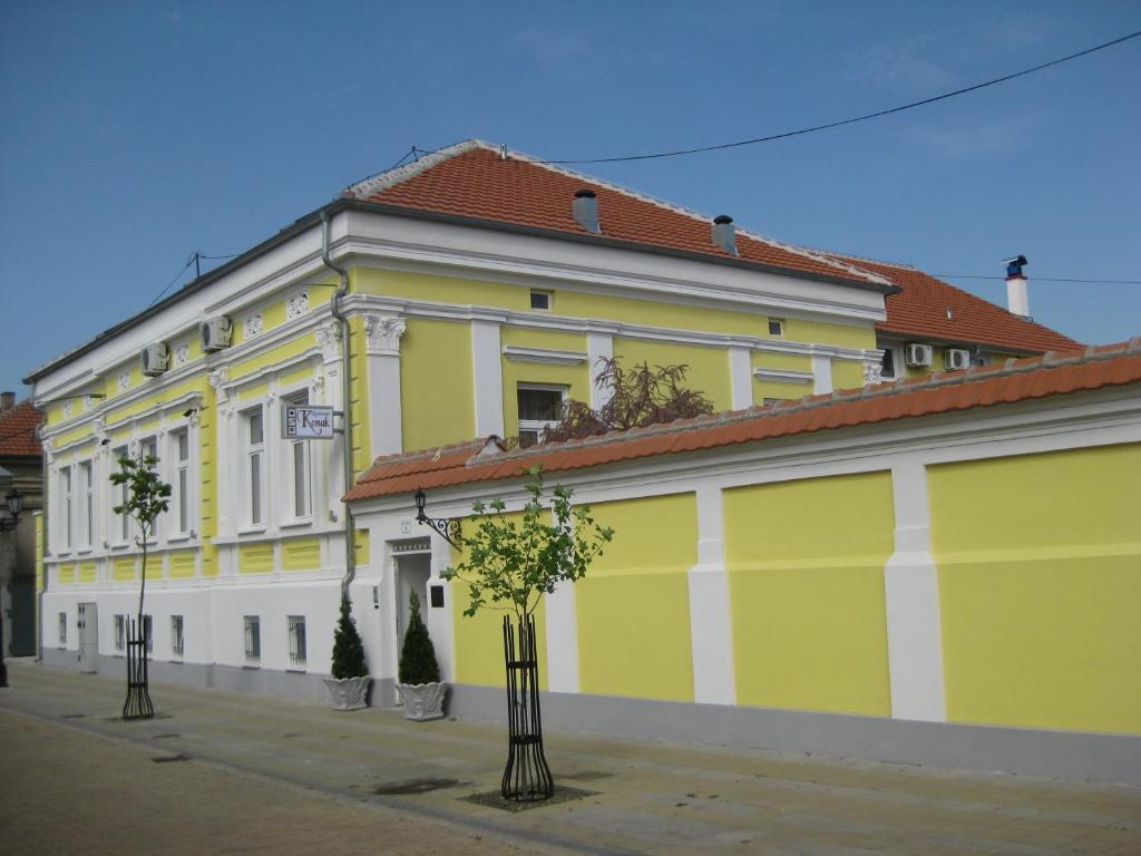 um edifício amarelo e branco com árvores em frente em Konak em Požarevac