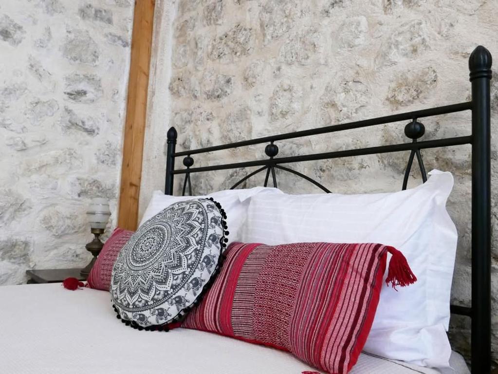 a black bed with red and white pillows on it at Το Λαϊνάκι by Fox Tale Guest House in Fternón