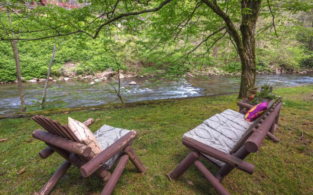 two chairs and a picnic table next to a river at On the River in Gatlinburg