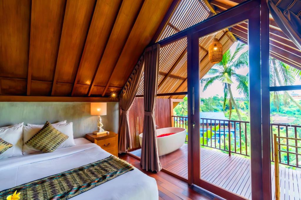 a bedroom with a bed and a balcony at The Suarsena Escape in Ubud