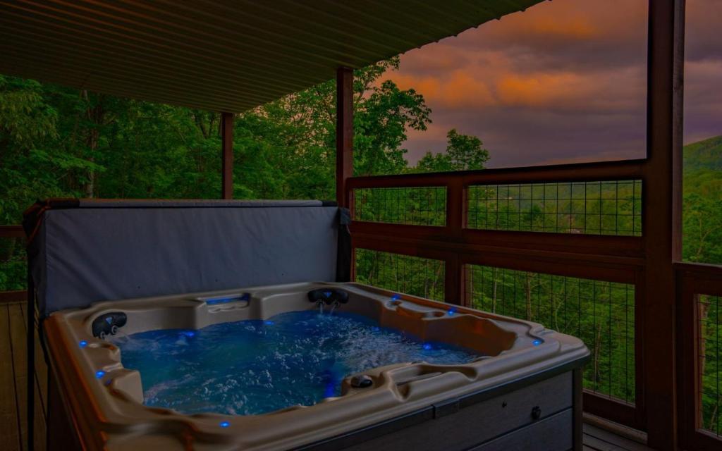 a hot tub on a porch with a view of a forest at Absolute Heaven in Gatlinburg