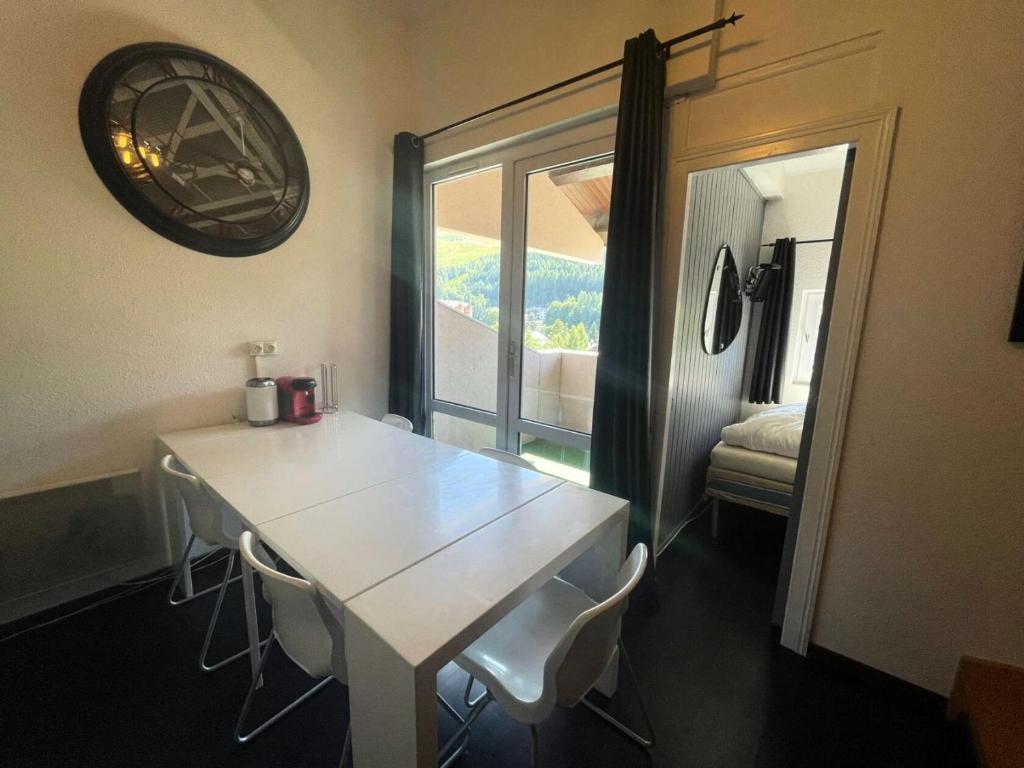 une table blanche et des chaises dans une pièce avec une fenêtre dans l'établissement Résidence Arc En Ciel C - Duplex coup de coeur en hauteur de station MAE-5441, à Vénosc