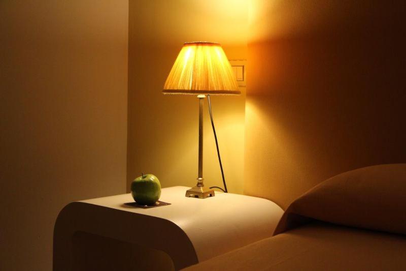 a lamp on a table with a green apple on it at Hotel Bouza in Ribadeo