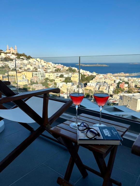 two glasses of red wine on a table on a balcony at Stonehill Suites Ano Syros in Ano Syros