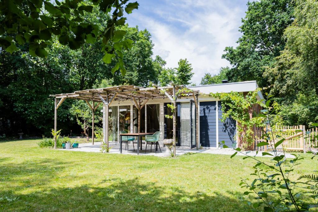 a pergola with a table in a yard at Bungalow Bosuil | 2 personen - Vakantiepark De Kremmer in Gasselte