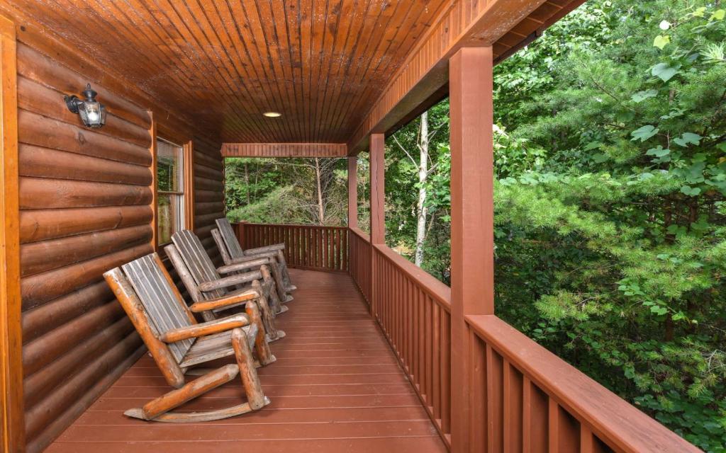 a porch with three rocking chairs on it at Think a Little Less in Gatlinburg