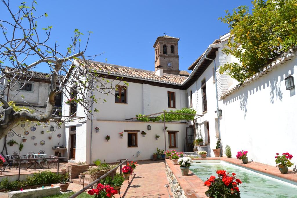 a white house with a courtyard and a clock tower at Apartamentos Carmen de Ramilla in Granada