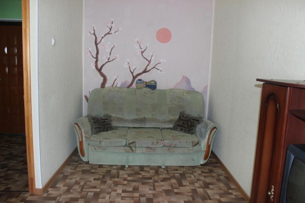 a couch in a room with a tree on the wall at Apartments on the River in Kamyshin